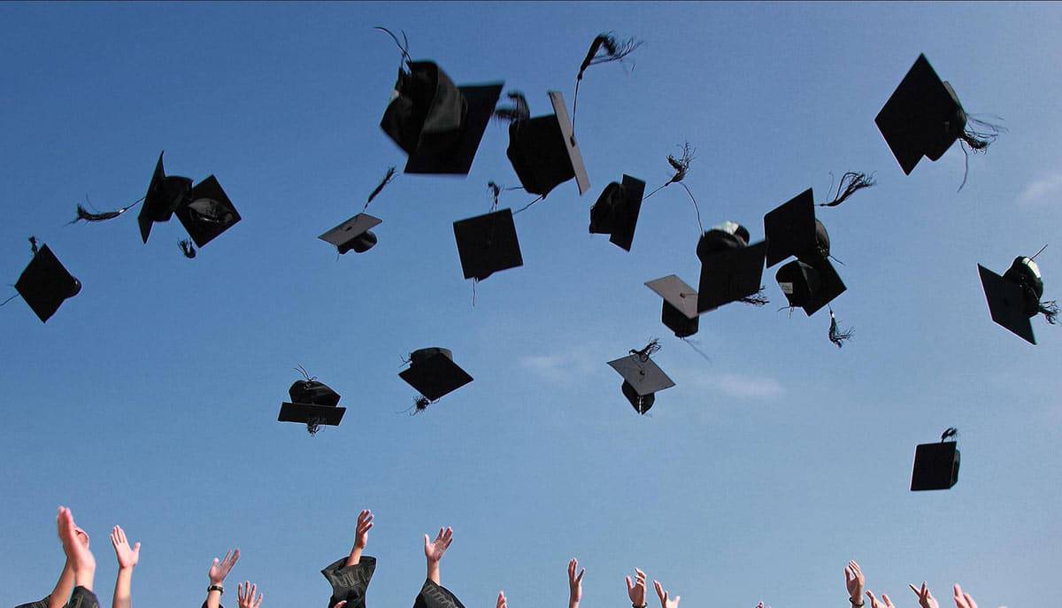 Graduates Educational view of graduates throwing up their hats against a blue sky