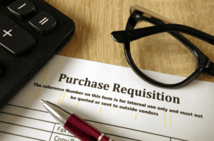 keyboard, glasses, purchase requisition form, and pen on desk